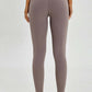 Model showcasing the back view of Millennia wide seamless band waist sports leggings in a stylish taupe color.