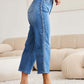 Woman wearing Judy Blue braid side detail wide leg jeans and white heels in modern living room