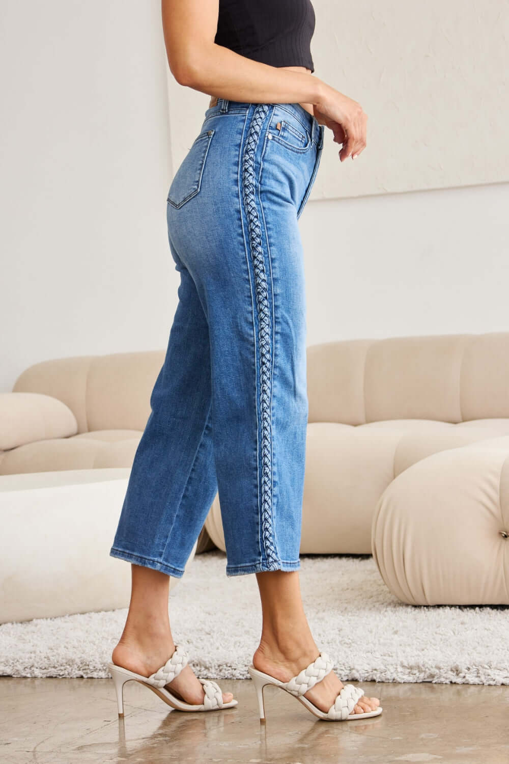 Woman wearing Judy Blue braid side detail wide leg jeans and white heels in modern living room