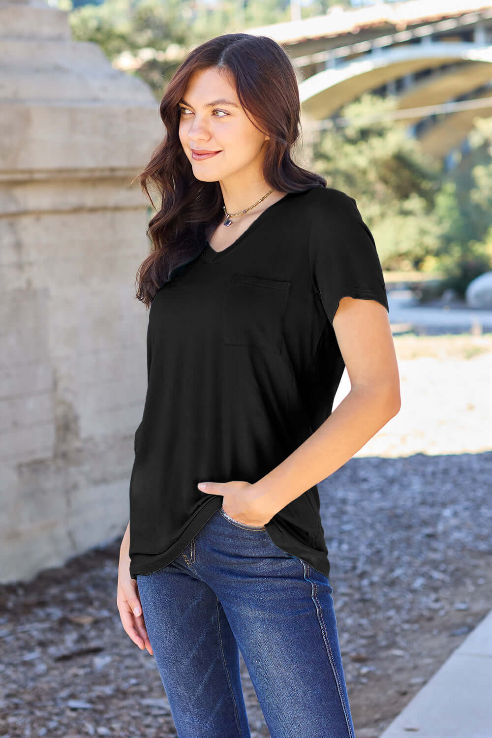 Woman wearing Basic Bae Bamboo Full Size V-Neck Short Sleeve T-Shirt in black, standing outdoors