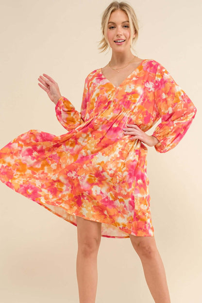 Woman wearing a full-size printed tie-back long sleeve dress with a vibrant floral design, showcasing elegant and fashionable styling.