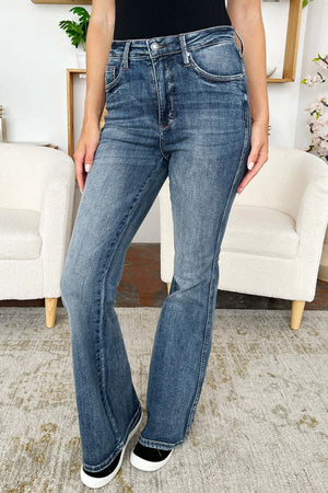 Woman wearing High Waist Tummy Control Flare Jeans by Judy Blue Jeans in a living room setting.