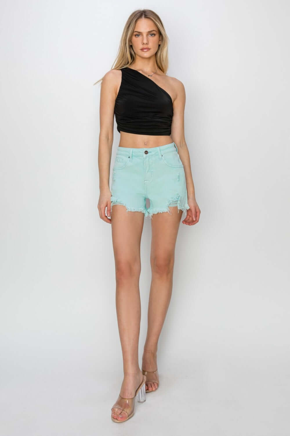 Mid waist frayed hem denim shorts by Risen Jeans styled with a chic black one-shoulder top, showcasing a casual summer look.