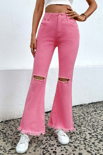 Woman wearing Bella Road distressed raw hem bootcut jeans in pink with slightly stretchy fabric, paired with white sneakers.