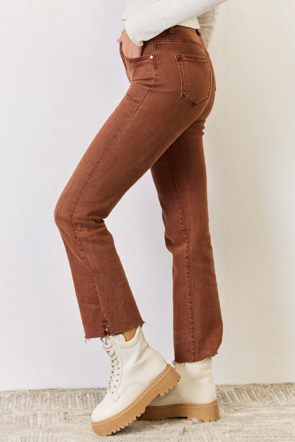 High Rise Tummy Control Straight Jeans by Risen Jeans with raw hem detail, side view in brown, paired with white ankle boots