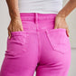 Close-up of back view of woman wearing pink high-waisted jeans with raw hem, showcasing tummy control and flattering fit. RFM Jeans.