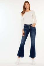 Woman wearing Kancan mid-rise button fly flare jeans in medium wash showing trendy silhouette and stylish button detail.