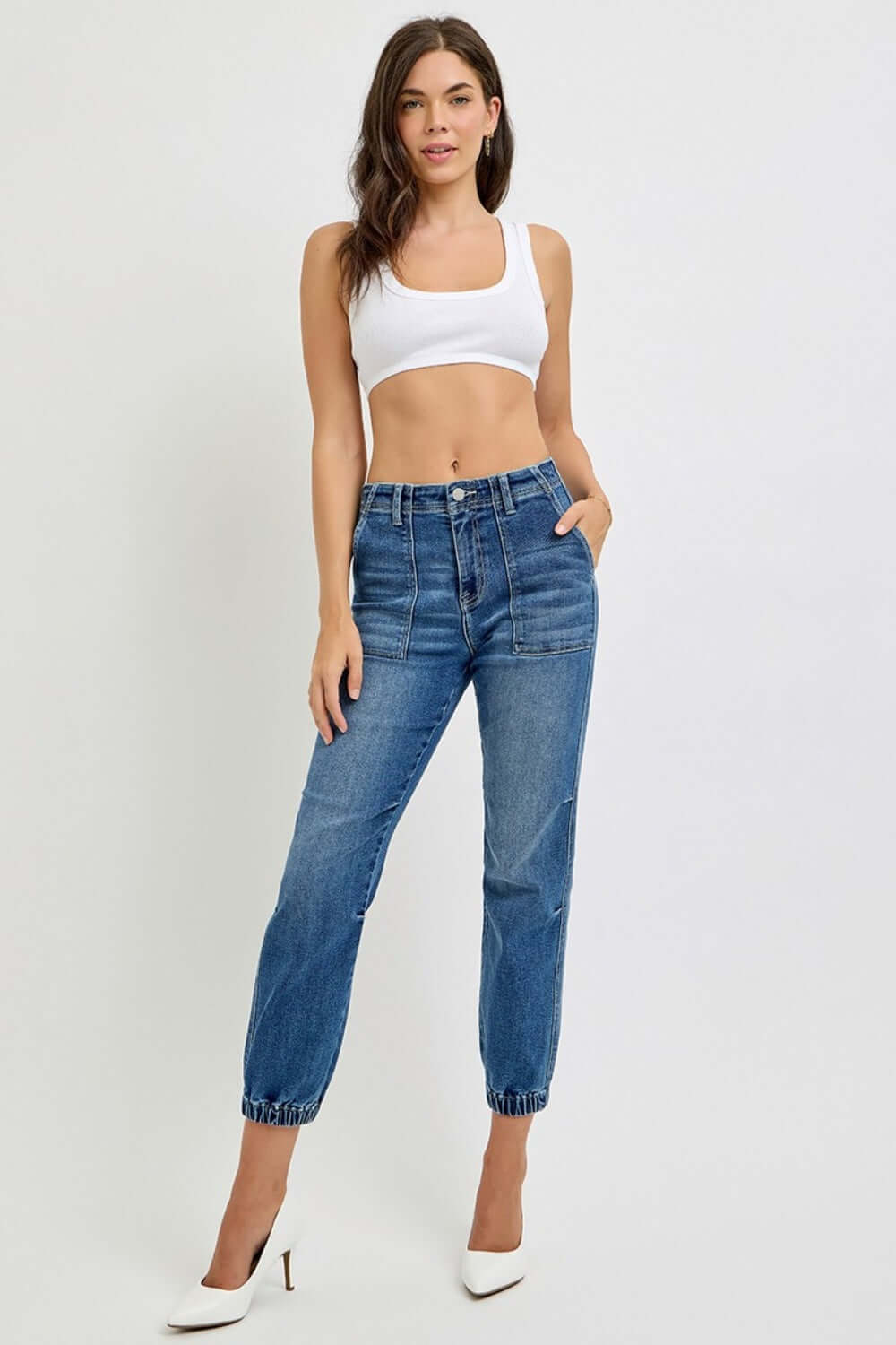 Stylish woman wearing RISEN high rise ankle jogger jeans with elastic cuffs and a white crop top, showcasing chic casual fashion.