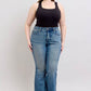 Model showcasing Judy Blue Mid Rise Tummy Control Vintage Wash Jeans with a black tank top and stylish sandals.