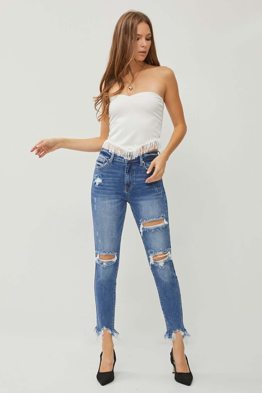 Woman wearing Distressed Frayed Hem Slim Jeans by Risen Jeans, showcasing trendy ripped details and a flattering slim fit.