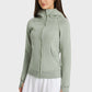 Woman wearing a light green Millennia Zip Up Seam Detail Hooded Sports Jacket, ready for outdoor activities.