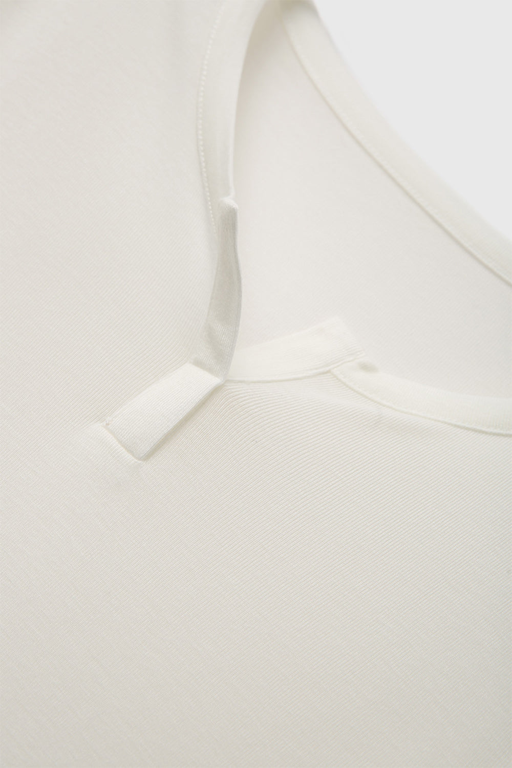 Close-up of Basic Bae Notched Long Sleeve T-Shirt's unique neckline in soft white fabric, showcasing its comfy and stylish design.