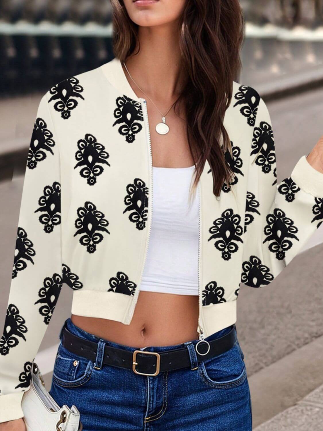 Woman wearing Bella Road Printed Zip Up Long Sleeve Jacket with black playful print, paired with jeans and a white top.