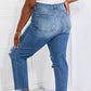 Back view of Emily High Rise Relaxed Jeans in blue with distressed knees, featuring a casual cropped fit, worn with a white top. Risen Jeans.