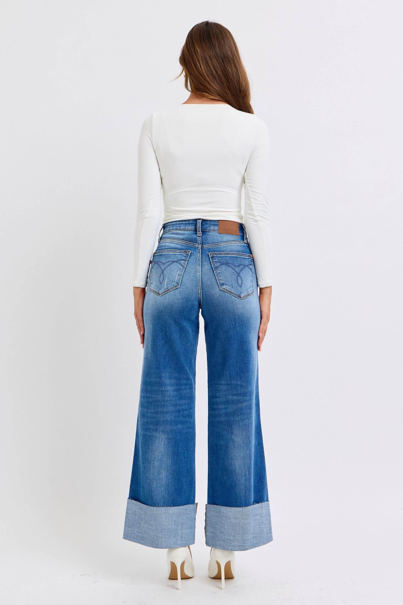 Back view of a model wearing Judy Blue distressed high waist wide leg jeans and a white fitted top.