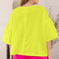 Woman wearing bright yellow oversized shirt and pink shorts, viewed from the back.