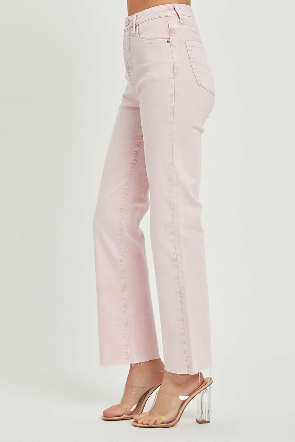 High-rise pink straight jeans with raw hem detail and tummy control feature for a flattering fit, shown on a model with clear heels.