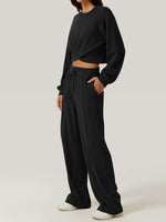 Woman wearing Bella Road Crisscross Round Neck Top and Drawstring Pants Set in black, showcasing a casual and stylish look.