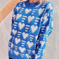 Woman wearing Bella Road Heart Contrast Long Sleeve Dropped Shoulder Sweater in blue with white heart patterns.