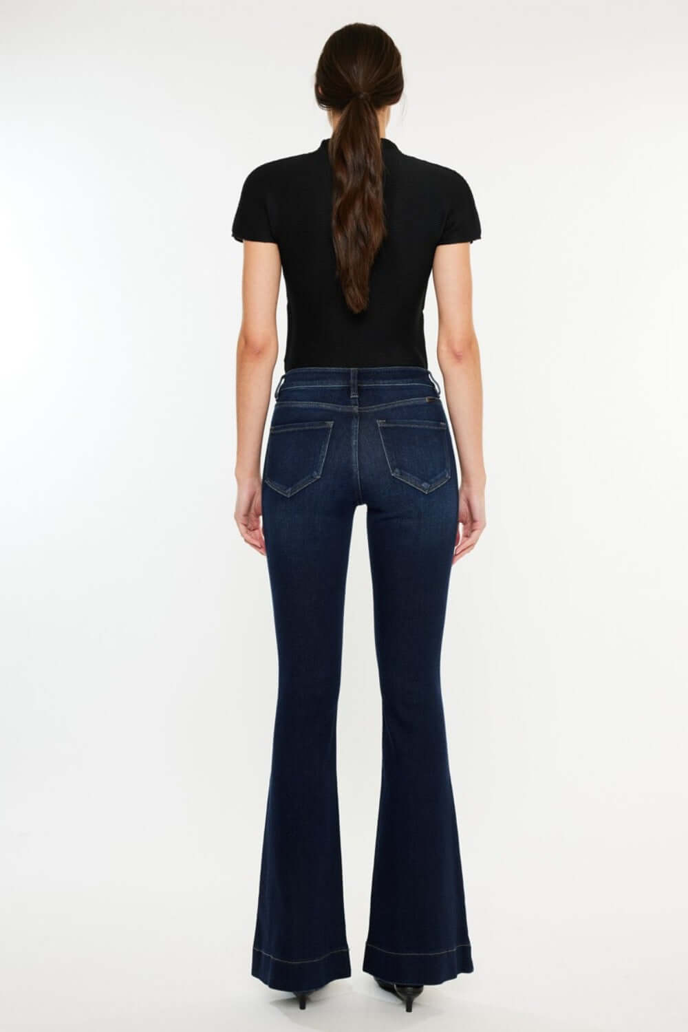 Woman wearing Kancan High Rise Slim Flare Jeans in dark wash, showcasing the sleek and sophisticated fit from the back view.