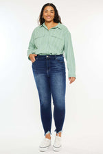 Woman wearing High Rise Frayed Ankle Skinny Jeans and a light green button-up shirt.