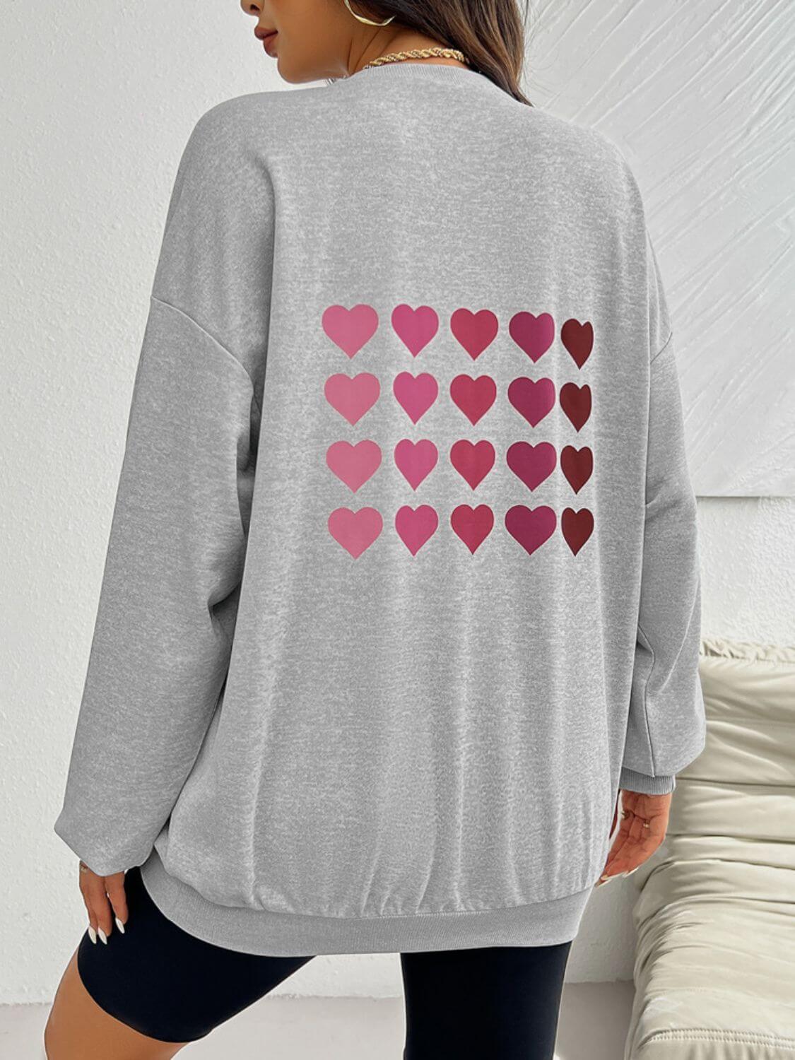 Woman wearing Devine Heart Dropped Shoulder Long Sleeve Sweatshirt with heart prints on the back.