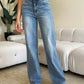 Woman wearing High Waist Wide Leg Judy Blue Jeans standing in a modern living room