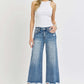 Woman wearing High Rise Cropped Flare Jeans from Risen Jeans, styled with a white tank top and sandals, showcasing the trendy denim look