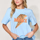 Woman wearing MAMA round neck short sleeve T-shirt in light blue with leopard print design, paired with blue jeans.