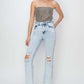 Model wearing Risen Jeans high rise distressed ankle jeans, styled with a strapless top and heels for a chic look.