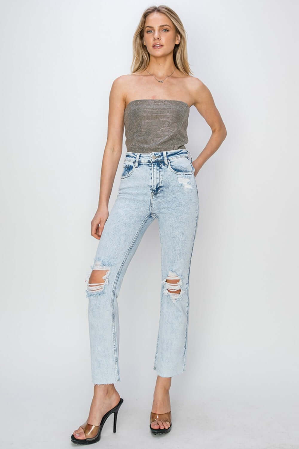 Model wearing Risen Jeans high rise distressed ankle jeans, styled with a strapless top and heels for a chic look.