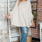 Woman wearing Bella Road Round Neck Batwing Sleeve Sweater with jeans and hat, posing stylishly indoors.