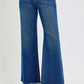 Risen tummy control high rise wide leg jeans with pockets and trendy frayed hem showcased with stylish black sandals.