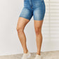 Woman wearing Tummy Control Double Button Bermuda Denim Shorts from Judy Blue Jeans, showcasing stylish and comfortable casual fashion.