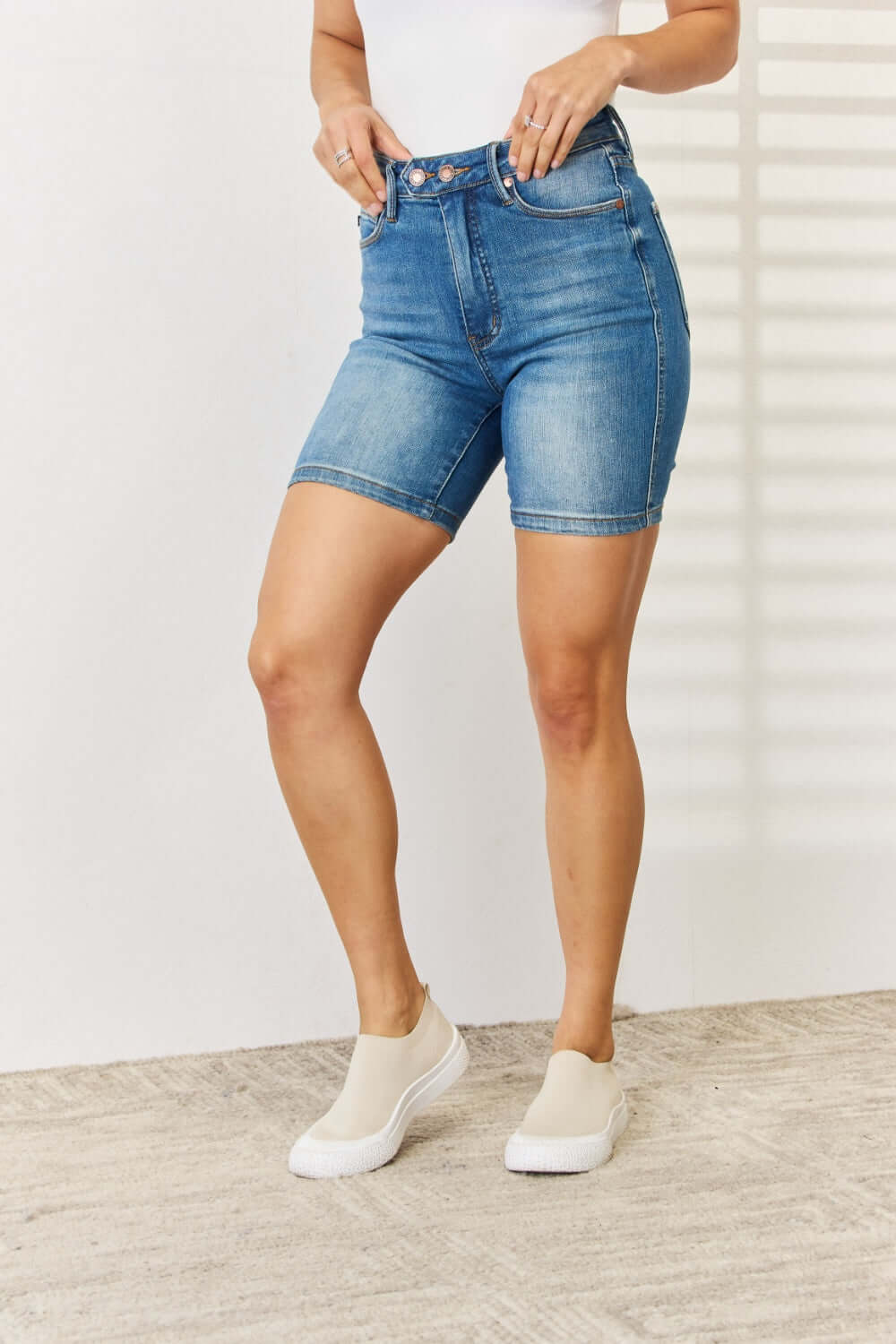 Woman wearing Tummy Control Double Button Bermuda Denim Shorts from Judy Blue Jeans, showcasing stylish and comfortable casual fashion.