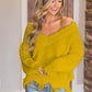 Woman in Bella Road yellow frayed hem dropped shoulder sweater, smiling indoors.