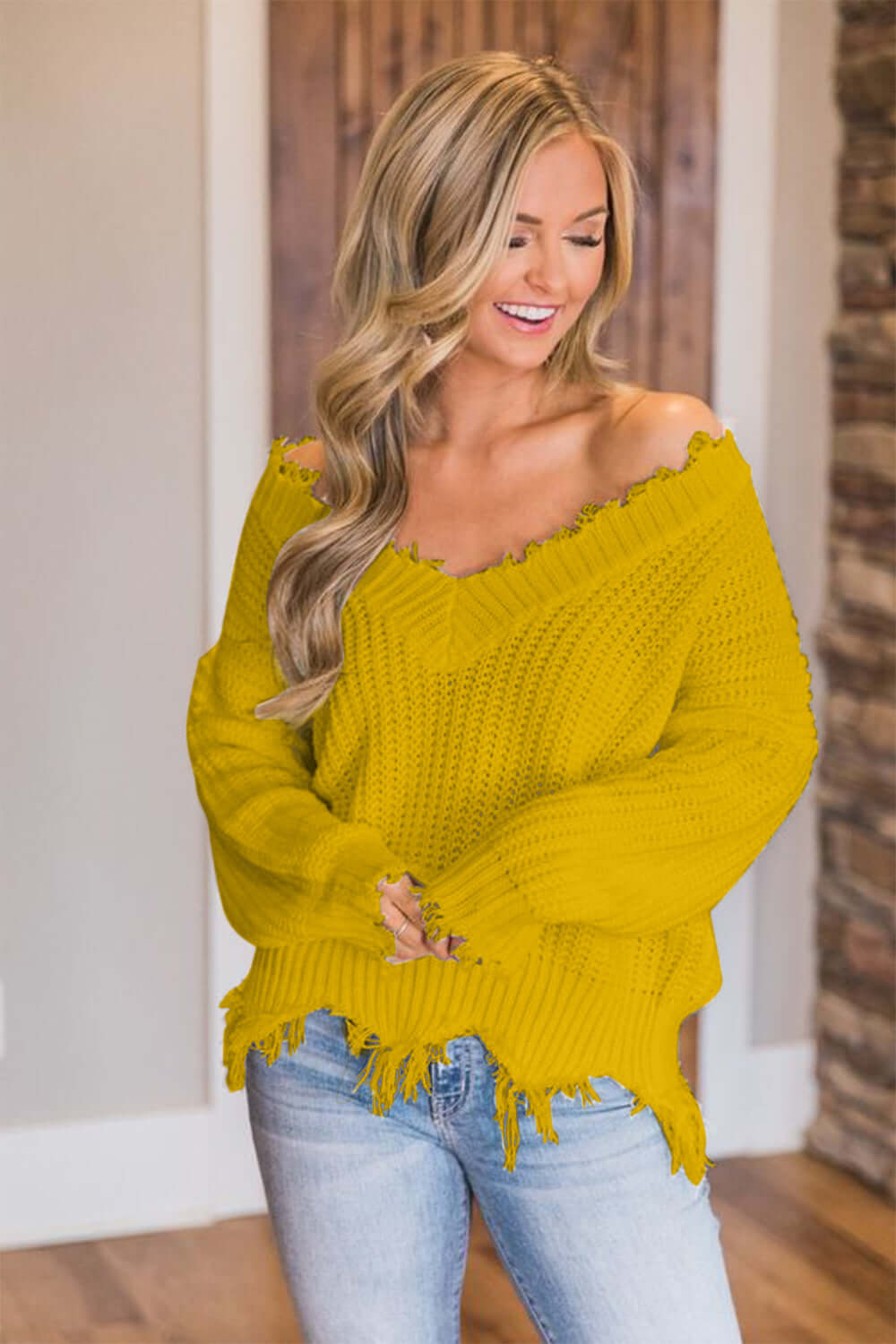 Woman in Bella Road yellow frayed hem dropped shoulder sweater, smiling indoors.