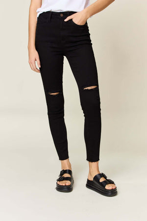 Model wearing black distressed tummy control high waist skinny jeans by Judy Blue Jeans with white top and black sandals.