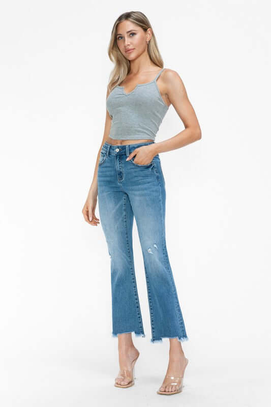 Model wearing bytos Raw Hem Distressed Mid Rise Crop Jeans with a gray crop top, showcasing modern denim style.