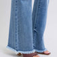 Trendy raw hem high rise bootcut jeans paired with stylish brown slide sandals, showcasing a chic casual look.