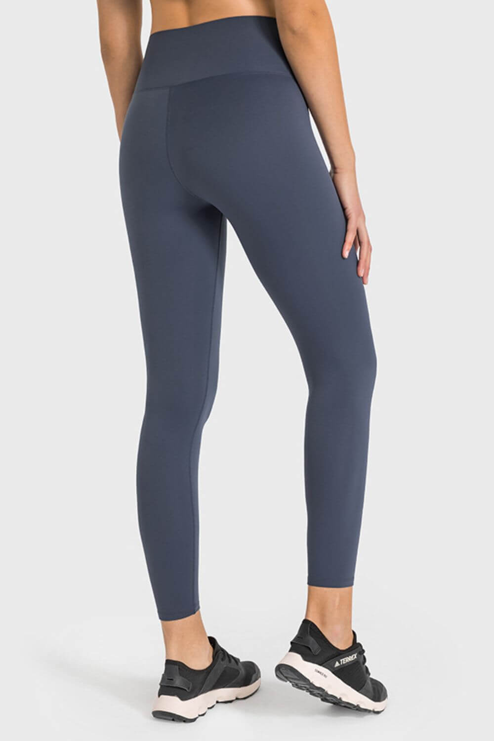 Woman wearing Millennia High Waist Ankle-Length Yoga Leggings in navy, showcasing the stylish high waist and ankle fit.