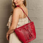 Woman carrying Nicole Lee USA Amy Studded Bucket Bag in red pebbled vegan leather with stud and zipper detailing