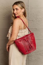 Woman carrying Nicole Lee USA Amy Studded Bucket Bag in red pebbled vegan leather with stud and zipper detailing