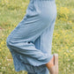 Woman wearing Bella Road Raw Hem Wide Leg Jeans in a grassy field, showcasing the raw hem and wide leg design.