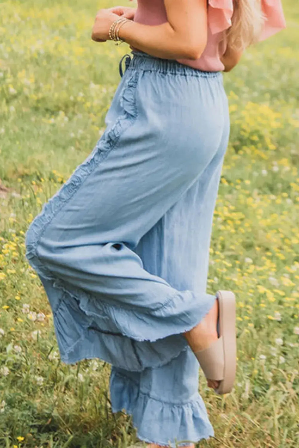 Woman wearing Bella Road Raw Hem Wide Leg Jeans in a grassy field, showcasing the raw hem and wide leg design.