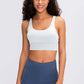 Model wearing Millennia Double X Sports Bra in white, paired with blue workout shorts, showcasing a stylish athletic look.