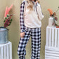 Stylish woman in drawstring hooded top and plaid pants lounge set, smiling against a colorful backdrop. Perfect for cozy lounging!