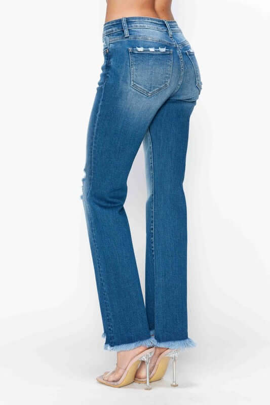 Woman showcasing bytos raw hem distressed mid rise straight jeans from the back, highlighting the edgy style and flattering fit.