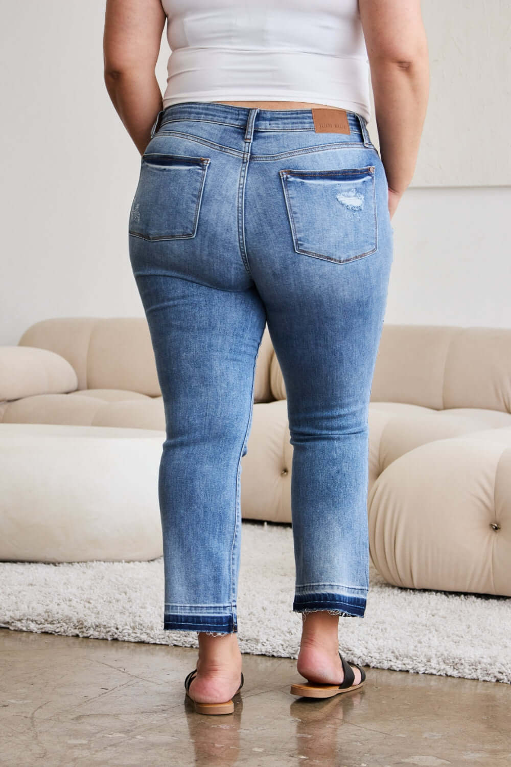 Woman wearing Judy Blue release hem cropped bootcut jeans, rear view, showcasing trendy denim fashion.