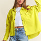 Stylish woman wearing a yellow snap down long sleeve high low shacket and denim shorts, showcasing a trendy and versatile look.